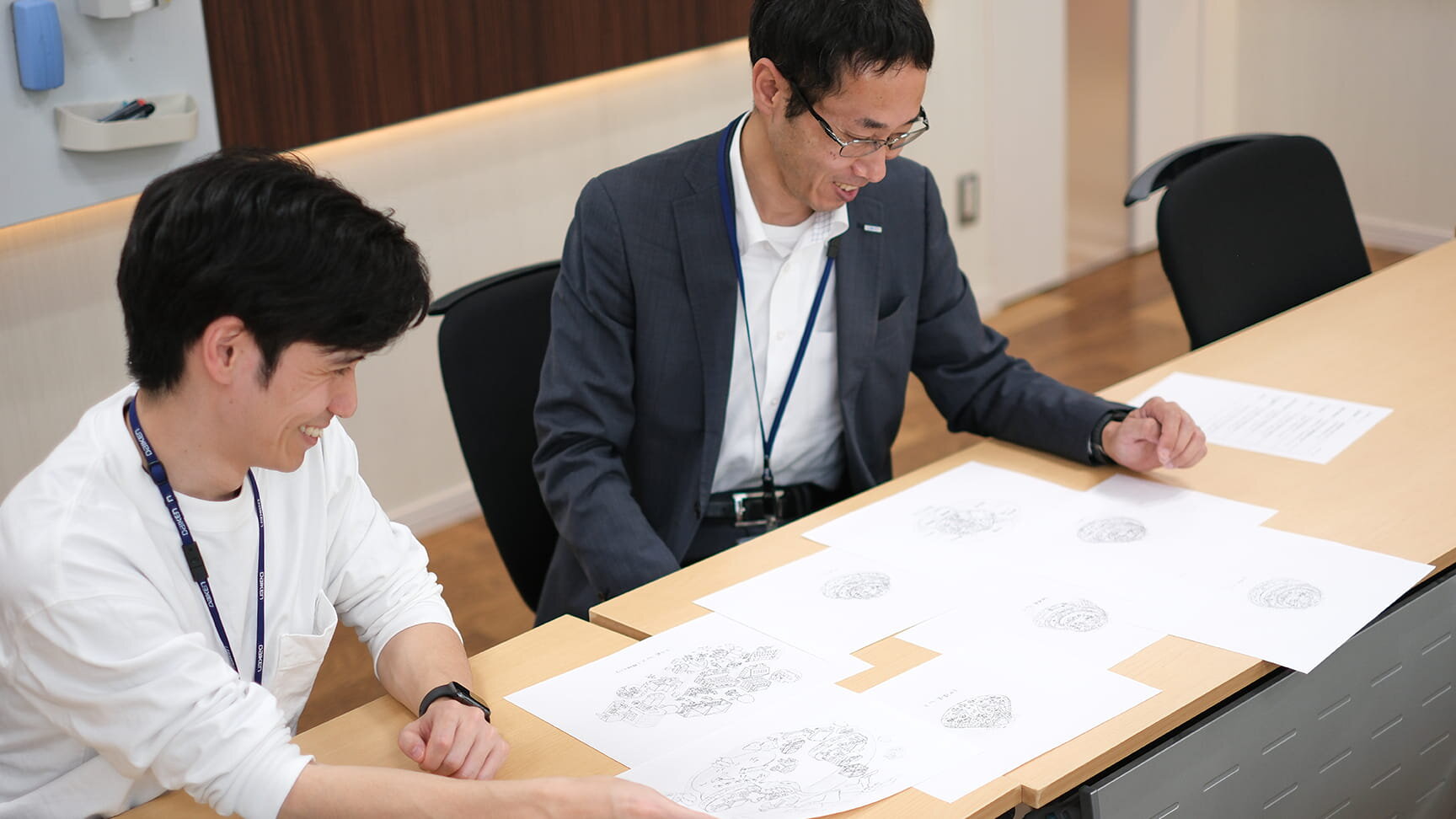 石黒さんと岩本さんがイラストの手書きラフを見ている様子